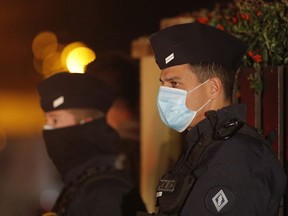 French police officers stand outside a high school after a history teacher who opened a discussion with students on caricatures of Islam's Prophet Muhammad was knifed.