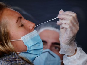 A health worker, wearing a protective suit and a face mask, administers a nasal swab to a patient in a temporary testing site for the coronavirus disease (COVID-19) at the Zenith Arena in Lille, France, October 26, 2020.