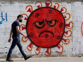 A Palestinian man walks past a coronavirus-themed mural amid the coronavirus disease (COVID-19) outbreak, in Gaza City October 4, 2020.
