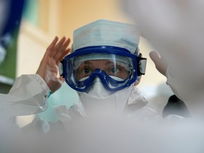 A medic puts on a protective suit ahead of a shift to treat patients suffering from the coronavirus disease.