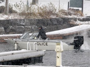 An Ontario Provincial Police officer prepares to bring a police boat back to shore Sunday afternoon in Brockville after police recovered the remains of a missing diver from the St. Lawrence River.