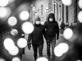 People walk down George Street by Christmas lights as the snow started Sunday, Nov. 22, 2020, in the downtown core.