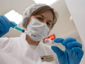 A health worker draws the 'Gam-COVID-Vac', also known as 'Sputnik V', COVID-19 vaccine, developed by the Gamaleya National Research Center for Epidemiology and Microbiology and the Russian Direct Investment Fund (RDIF), from a vial during a trial at the City Clinic #2 in Moscow, Russia, on Thursday, Nov. 26, 2020.