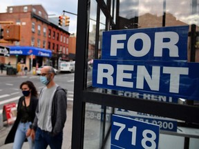FILE: People walk past a "for rent" sign.