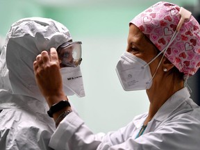 A nurse is helped by a collegue to put on her personal protective equipment (PPE) at the Intensive Care Unit (ICU) for the Covid-19 (the novel coromavirus) cases, in the San Filippo Neri hospital in Rome, on October 29, 2020.