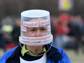 A participant wears a bucket as protection during a demonstration against the coronavirus restrictions in Munich, southern Germany, on November 1, 2020.