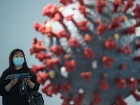 This photo taken on November 11, 2020 shows a woman looking at a model of the COVID-19 coronavirus at the second World Health Expo in Wuhan, in China's central Hubei province, where the coronavirus was first detected in December 2019.