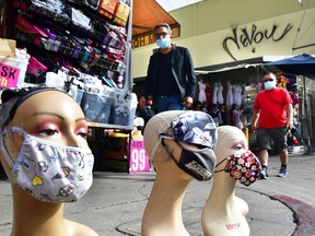 Pedestrians wearing face masks walk past a display of mannequin heads also wearing face masks: Just wait until it gets really cold, soggy and blizzardy out there.