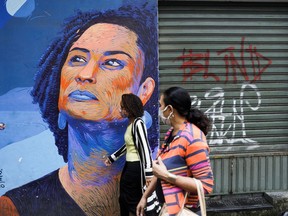 Women walk past graffiti art depicting late activist and councilwoman Marielle Franco, which is part of the artistic project Negro Muro (Black Wall), in Rio de Janeiro, Brazil, November 20, 2020.