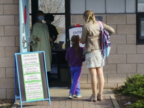 A nurse welcomes a mother and her daughter at a COVID-19 testing clinic in Montreal, Monday, Nov. 9, 2020. A new survey suggests the onset of the COVID-19 pandemic may have boosted public trust in science and scientists.