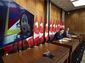 Conservative MP Garnett Genuis and Pierre Paul-Hus listen to Chemi Lhamo during a news conference in Ottawa, Thursday, Nov. 26, 2020. Canadians who say they have been victims of threats and intimidation by Chinese, Iranian and Russian foreign agents are saying that domestic police forces are ill-equipped to deal with their concerns.