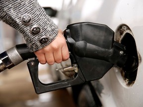 A file photo of a woman pumping gas into her vehicle.