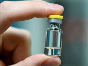 A worker of German vaccine maker IDT Biologika shows a sample ampoule.