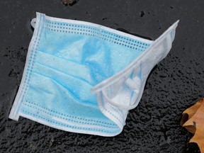 A thrown-away face mask is seen on a street.