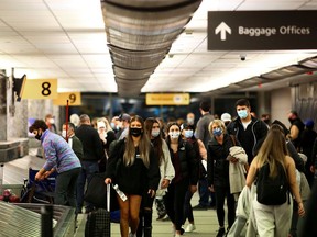 FILE PHOTO: Travelers wearing protective face masks to prevent the spread of the coronavirus disease (COVID-19) reclaim their luggage at the airport in Denver, Colorado, U.S., November 24, 2020.