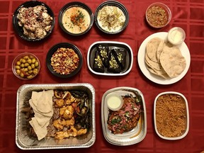 Assorted dishes from Fairouz Cafe, including clockwise from top left: fried cauliflower, hummus, toum, eggplant esme, pita, freekeh pilaf, eggplant mashi, meat platter, olives, nuts and pomegranate, chocolate cake.