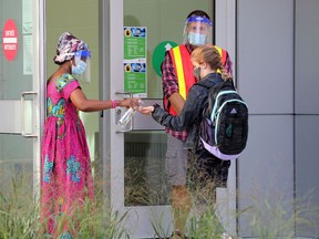 Staff members welcome a student École Horizon-Jeunesse in Ottawa on the first day of classes there on Sept. 3.