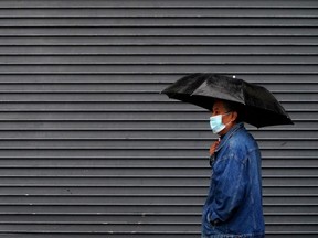 A man walks in the rain with an umbrella.