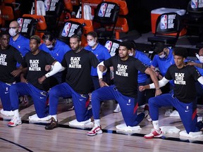 Philadelphia 76ers players kneel in honour of the Black Lives Matter movement during the national anthems prior to an NBA game against the Toronto Raptors Aug. 12 in Lake Buena Vista, Florida.