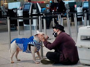 A traveller wearing a face covering sits with a dog at Terminal 2 of Heathrow Airport in west London on December 21, 2020, as a string of countries around the world banned travellers arriving from the UK, due to the rapid spread of a new, more-infectious coronavirus strain.