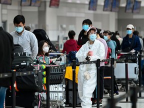 People line up and check in for an international flight at Pearson International airport during the COVID-19 pandemic in Toronto on Wednesday, Oct. 14, 2020.