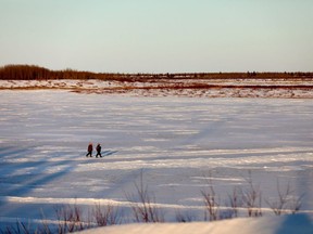 Files: Two people walk across the frozen Severn River alongside Fort Severn, Ont., near Hudson Bay, Friday, April 27, 2018. Scientists say a year in which almost 200 tundra lakes drained away could point to what's in store for Canada's North.