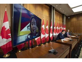 Conservative MP Garnett Genuis and Pierre Paul-Hus listen to Chemi Lhamo during a news conference in Ottawa, Nov. 26, 2020. A Tibetan-Canadian, she was threatened here in Canada for her activism.