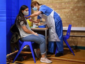 A nurse administers the Pfizer/BioNTech COVID-19 vaccine to a woman in Wales