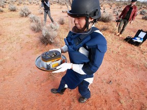 In this handout image from Japan Aerospace Exploration Agency (JAXA), a member of JAXA collects Hayabusa2's capsule carrying the first extensive samples of an asteroid after it landed in the Woomera restricted area, Australia, December 6, 2020.
