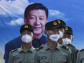 Soldiers of the People's Liberation Army's Honour Guard Battalion wear protective masks as they stand at attention in front of photo of China's president Xi Jinping at their barracks outside the Forbidden City, near Tiananmen Square, in Beijing.
