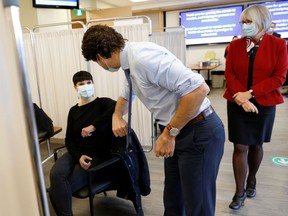 Prime Minister Justin Trudeau talks to the recipient of one of the first COVID-19 vaccinations at the Civic campus of The Ottawa Hospital. He's not being too forthcoming on details of pandemic spending, though.