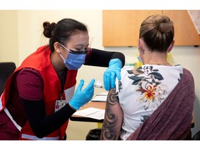 Nurse Venus Lucero administers the first Pfizer-BioNTech COVID-19 vaccine at the Civic Hospital to Jo-Anne Miner at a vaccination clinic in Ottawa on Tuesday.