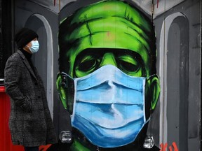 FILE: A man walks past a graffiti of a Frankenstein wearing a protective face mask on a doorway amid the spread of the coronavirus disease (COVID-19) pandemic, in Galway, Ireland.