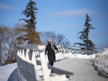 The bright sun helped to get people out and about on the chilly day Ottawa had Sunday Jan. 30, 2021.  A woman is well bundled for a walk as she crossed over the Flora Footbridge Saturday.