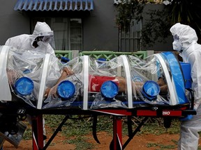 City of Tshwane's Special Infection Unit paramedics push a man inside an ambulance showing symptoms of COVID-19 coronavirus in the isolation chamber equipped with a negative pressure filtration system from his home in the north of Pretoria, South Africa, on January 15, 2021.