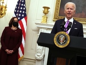 U.S. President Joe Biden speaks as Vice President Kamala Harris looks on during an event at the State Dining Room of the White House January 21, 2021 in Washington, DC. President Biden delivered remarks on his administration's COVID-19 response, and signed executive orders and other presidential actions.
