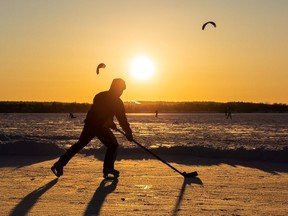 A man plays hockey as others kite ski on the Ottawa River's Britannia Bay.