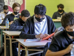 Masked high-students read at their desks.