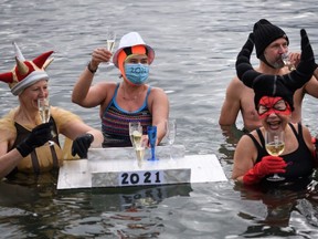 People celebrates with champagne during a New Year's traditional bathe at Lake Geneva with its 7 degree celsius waters in Geneva on January 1, 2021.