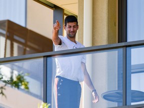 Novak Djokovic gestures from his hotel balcony in Adelaide, one of the locations where players have to quarantine for two weeks upon their arrival ahead of the Australian Open in Melbourne. The world No. 1 has asked local organizers to ease restrictions on players, allowing them either to leave their hotel rooms or be relocated to homes with tennis courts.