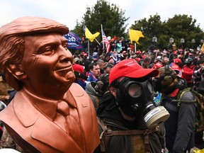 A supporter of US President Donald Trump wears a gas mask and holds a bust of him after he and hundreds of others stormed stormed the Capitol building on January 6, 2021 in Washington, DC.