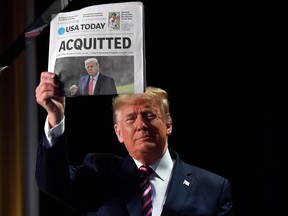 FILE: US President Donald Trump holds up a newspaper that displays a headline "Acquitted"  as he arrives to speak at the 68th annual National Prayer Breakfast on February 6, 2020 in Washington,DC.
