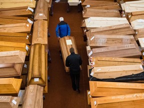 Employees store coffins, some marked with "infection risk" as others have "corona" scrawled in chalk, in the mourning hall of the crematorium in Meissen, eastern Germany, on January 13, 2021, amid the new coronavirus COVID-19 pandemic.
