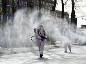 This photo taken on January 15, 2021 shows people in protective suits spraying disinfectant on a street at Gaocheng district, which was declared a high-risk area for Covid-19 in Shijiazhuang, in northern China's Hebei province.