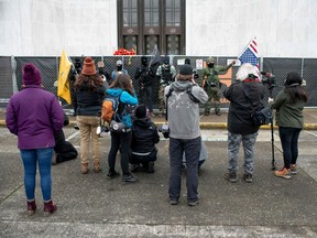 Members of the press outnumber a group of Boogaloo Boys posing for photographers outside the Oregon Sate Capitol Building in Salem on January 17, 2021, during a nationwide protest called by anti-government and far-right groups supporting US President Donald Trump and his claim of electoral fraud in the November 3 presidential election.