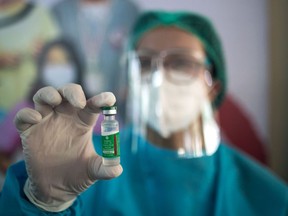 File: A health worker holds up a vial of COVID-19 vaccine