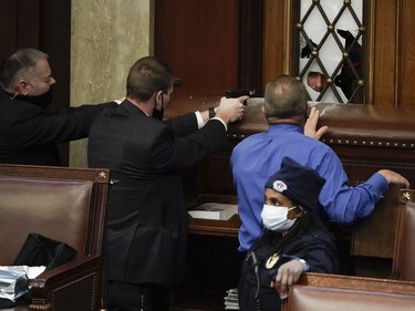 Police with guns drawn watch as protesters try to break into the House Chamber at the U.S. Capitol on Wednesday, Jan. 6, 2021, in Washington.