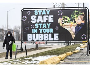 An Ontario women walks past a COVID-19 messaging sign. Economic recovery after the pandemic won't just depend on men.