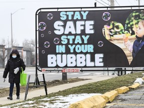 A women walks past a COVID-19 messaging sign during the COVID-19 pandemic in Mississauga