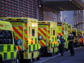 NHS workers walk next to a cue of ambulances outside the Royal London Hospital, in London, Britain January 12, 2021.